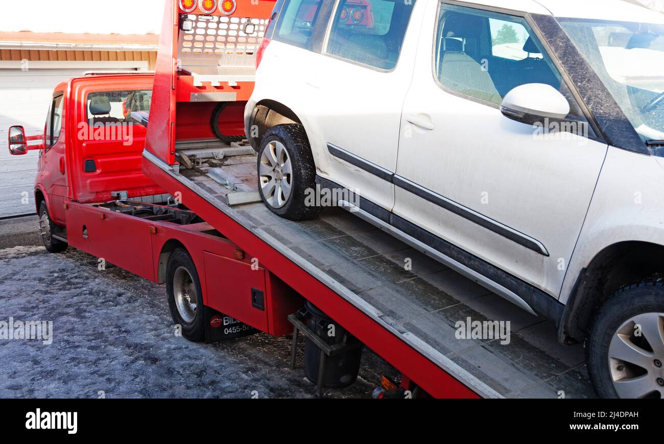 Umea, Norrland Schweden - 12. März 2022: Kaputtes Auto wurde von einem roten Abschleppwagen abgeholt Stockfoto