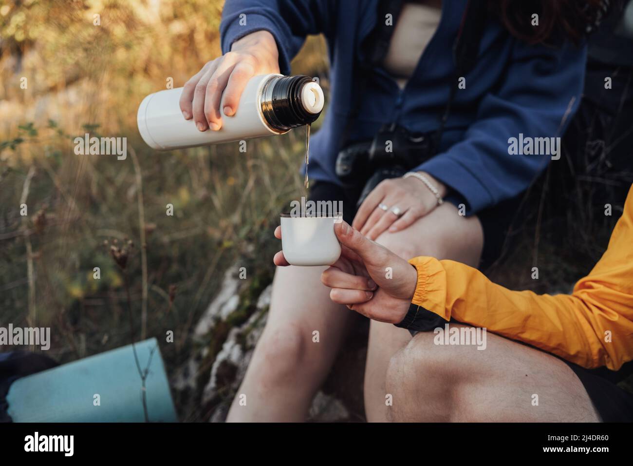 Zwei Reisende Mann und Frau machten während der Wanderung Halt, um heißen Tee aus dem Thermos zu trinken Stockfoto