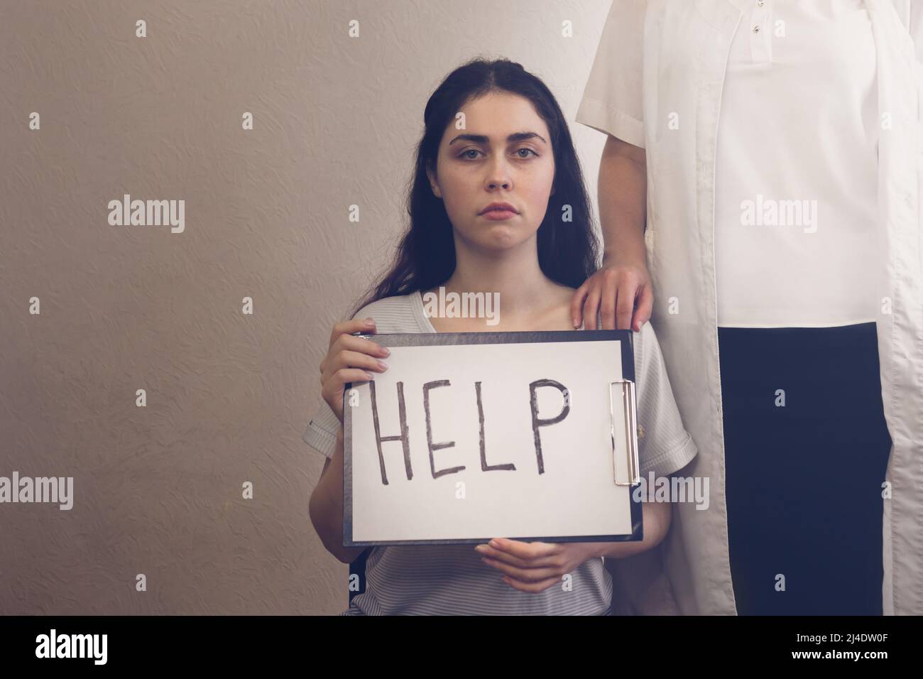 Mädchen in Depression hält eine Tablette mit der Aufschrift ''help und steht neben dem Arzt Stockfoto
