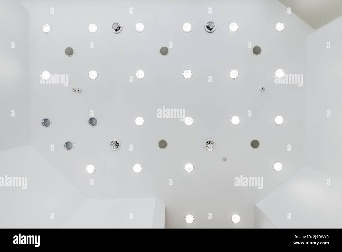 Abgehängte Decke mit Halogenstrahlern und Trockenmauerkonstruktion im leeren Raum in Wohnung oder Haus. Stretchdecke weiß und komplex. Stockfoto