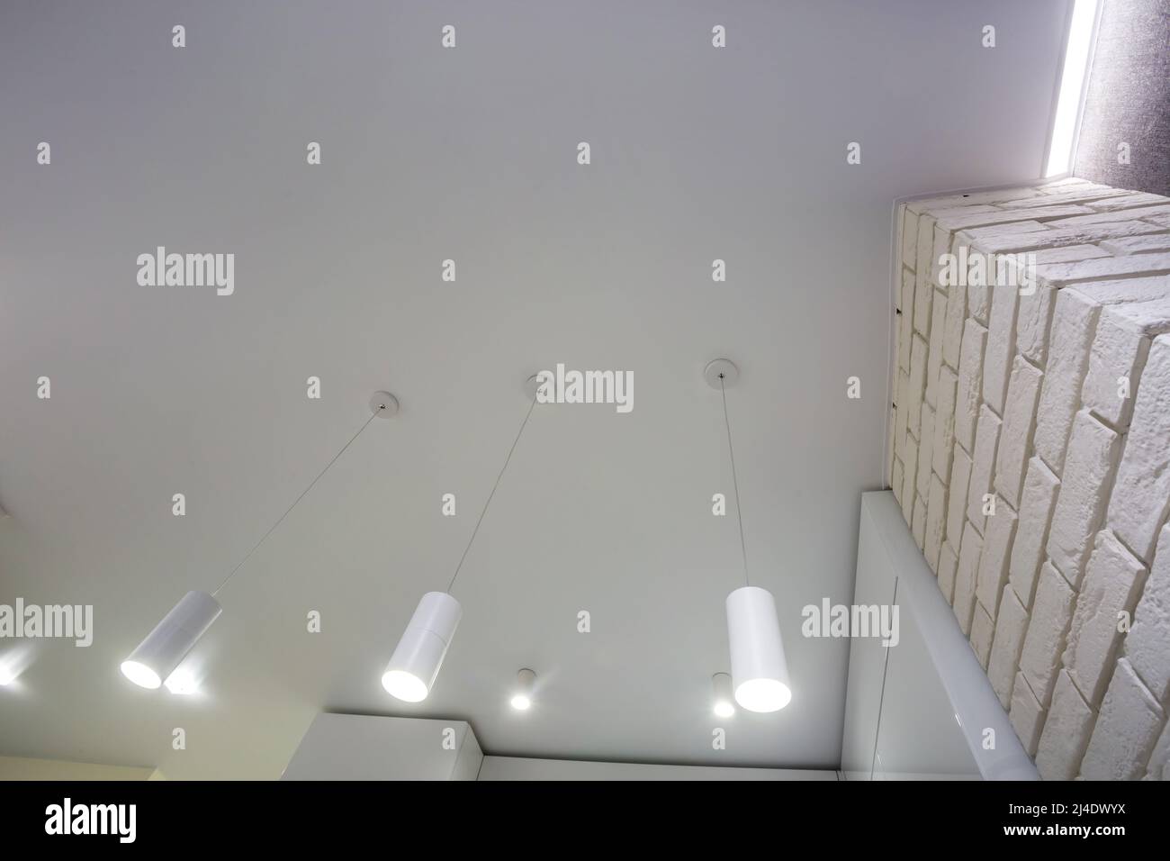 Abgehängte Decke mit Halogenstrahlern und Trockenmauerkonstruktion im leeren Raum in Wohnung oder Haus. Stretchdecke weiß und komplex. Stockfoto