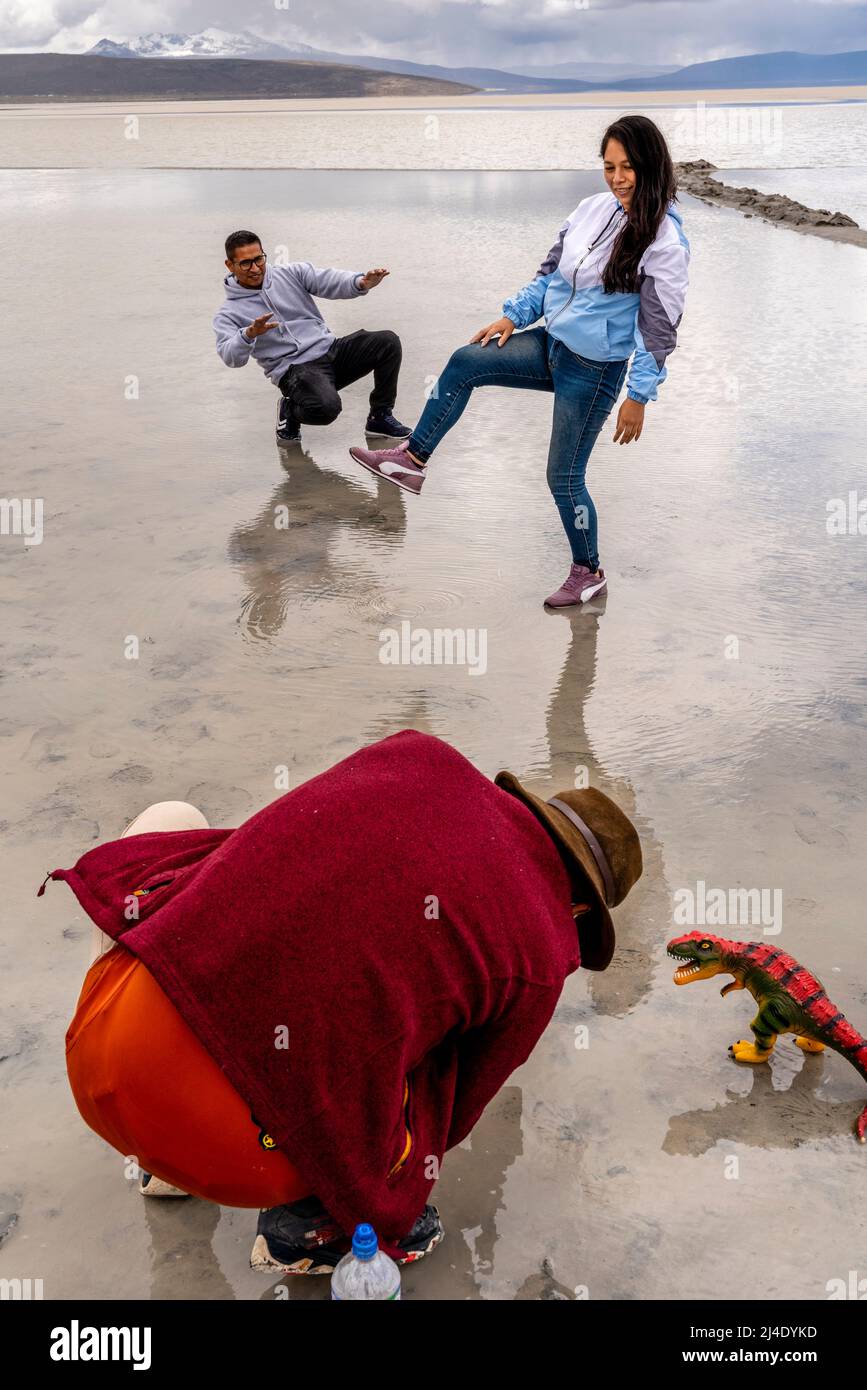 Besucher posieren für Fotos mit Einem Spielzeug-Dinosaurier am Salar de Moche (See Salinas) Salzsee in der Nähe der Stadt Arequipa, Region Arequipa, Peru. Stockfoto