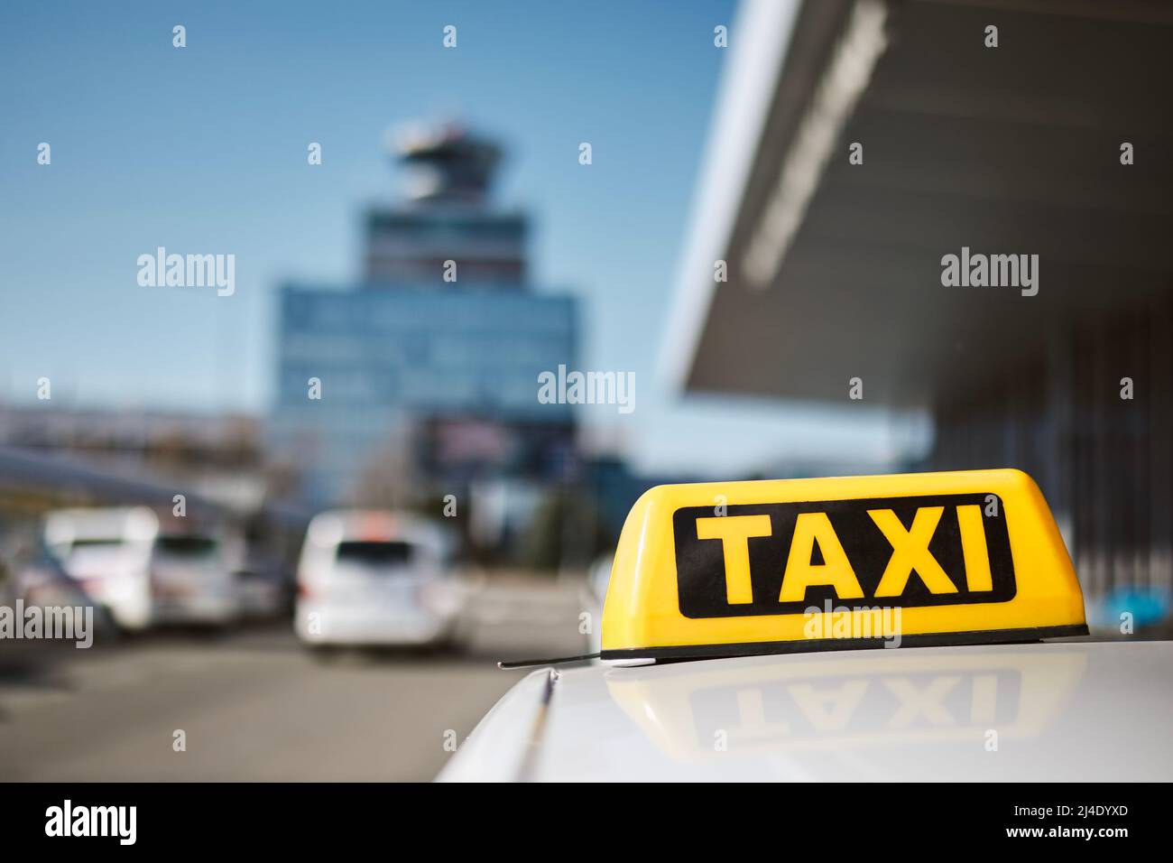 Selektiver Fokus auf Taxi-Schild auf dem Dach des Autos gegen Flughafen-Terminal. Stockfoto