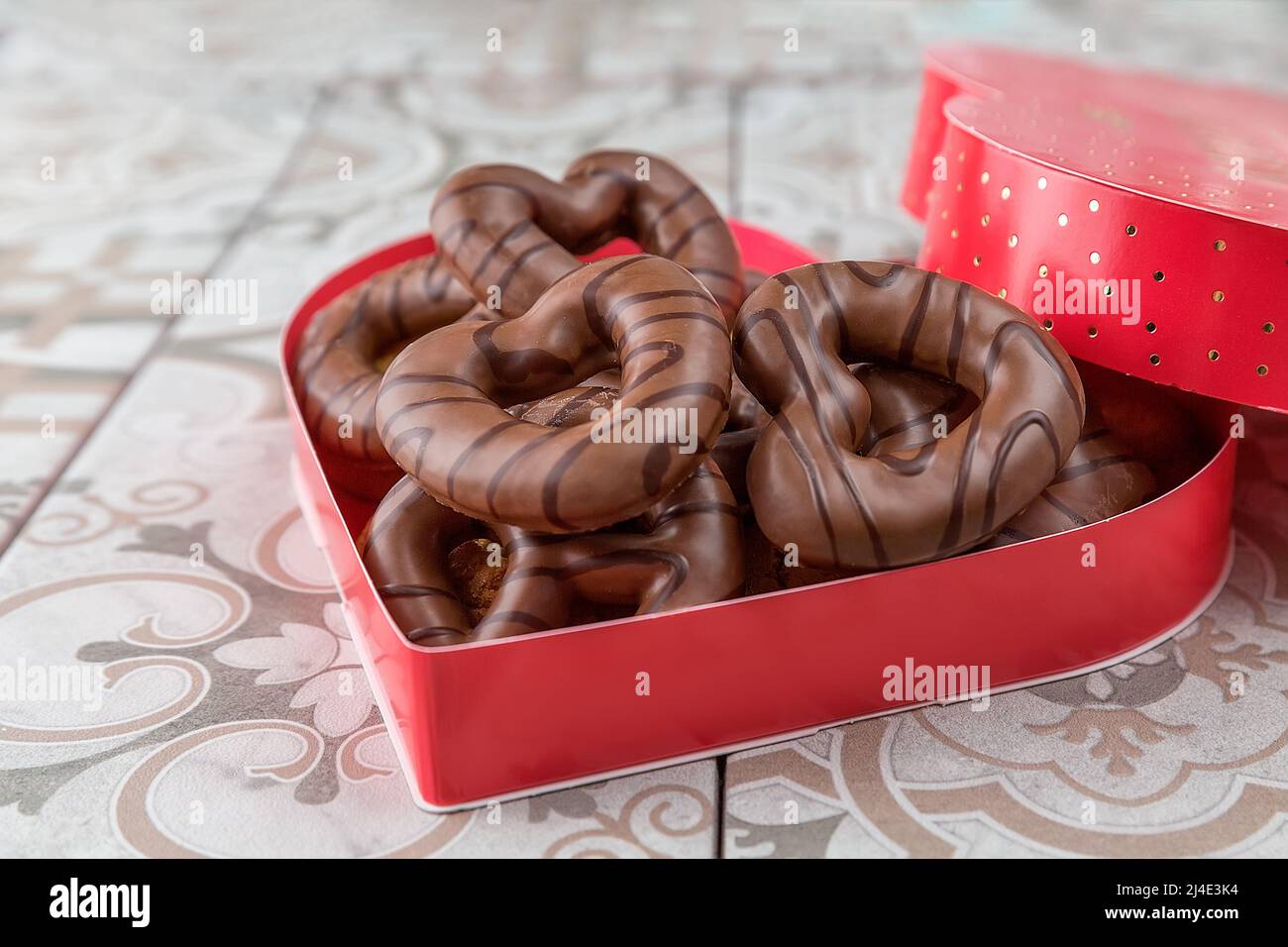 Valentinstag-Kekse. Mit Schokolade beschichtete Lebkuchenkekse. In einer roten herzförmigen Schachtel. Stockfoto