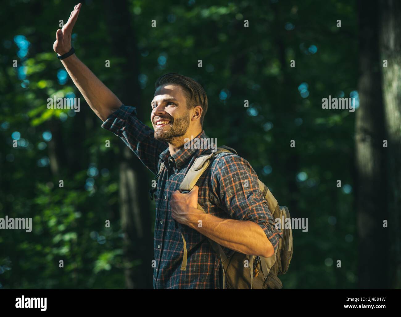 Glücklicher bärtiger Mann mit Rucksack, der im Wald herumläuft. Ökotourismus, Wandern, aktive Sommerferien. Stockfoto