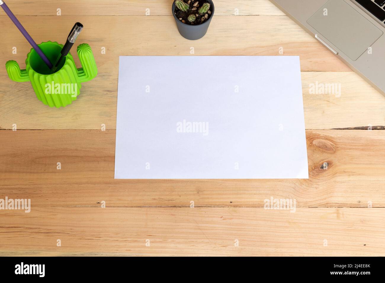 Leeres A4-Papier, das horizontal auf einem Holztisch mit Vorräten liegt Stockfoto