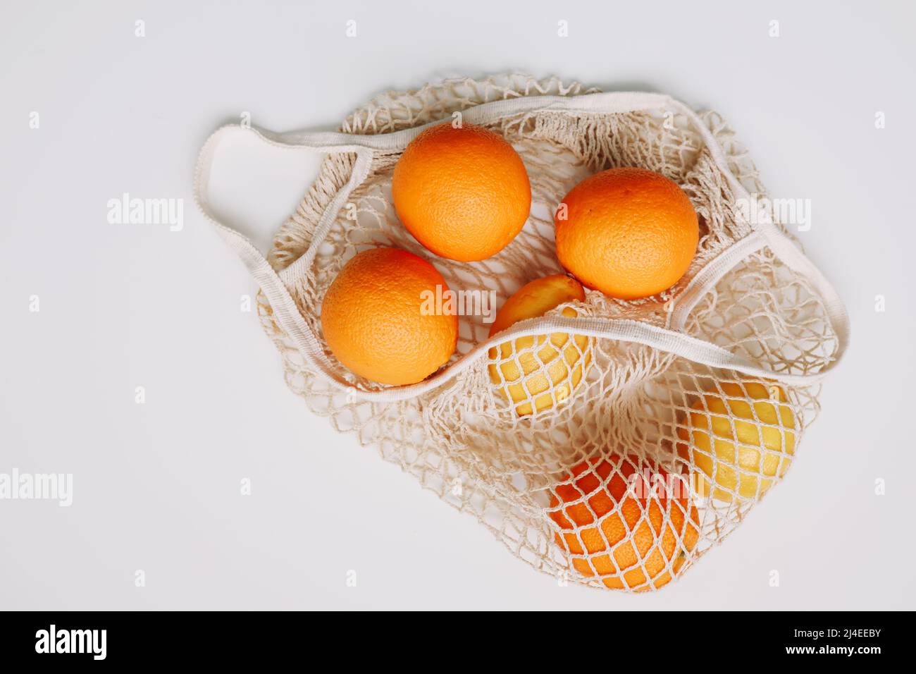 Zitronen in wiederverwendbarem Beutel. Zero Waste Konzept mit Saitentasche, Netztasche, Grosery Bag mit Früchten auf weißem Hintergrund, flaches Lay, Draufsicht, Kopierraum Stockfoto