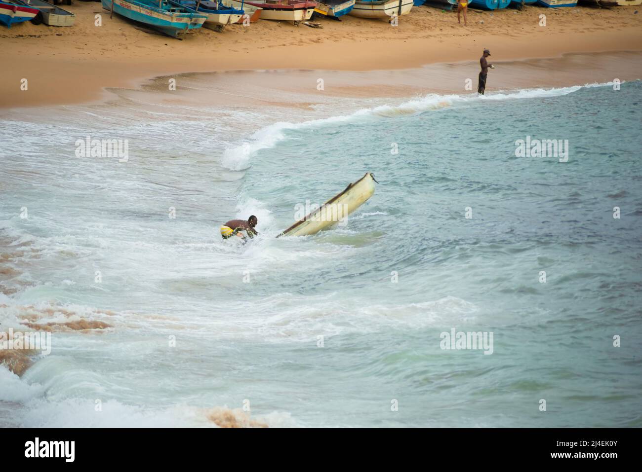 Ein Mann in einem Fischerboot am Strand des Rio Vermelho. Stadt Salvador, Bahia, Brasilien. Stockfoto