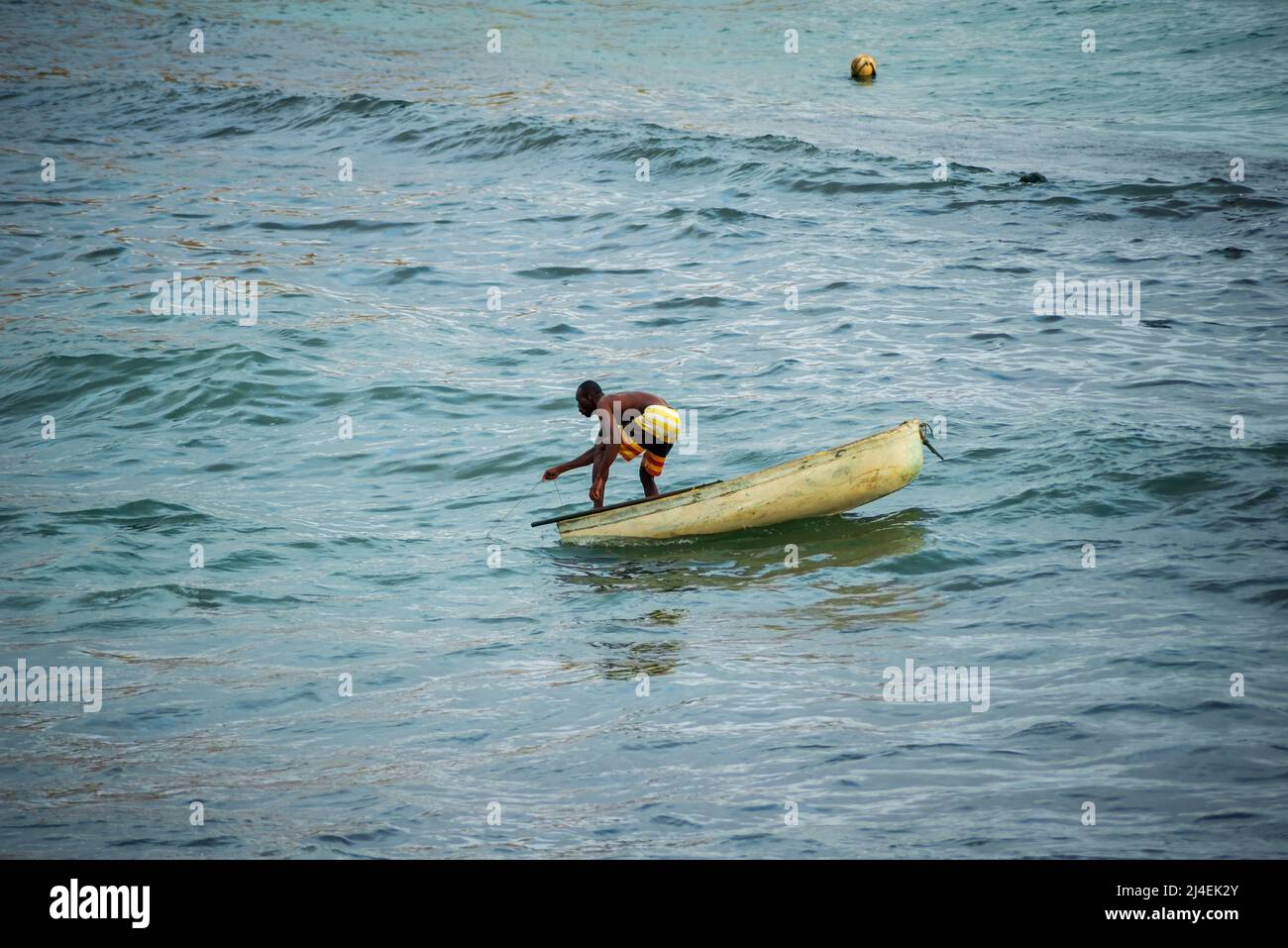 Ein Mann in einem Fischerboot am Strand des Rio Vermelho. Stadt Salvador, Bahia, Brasilien. Stockfoto