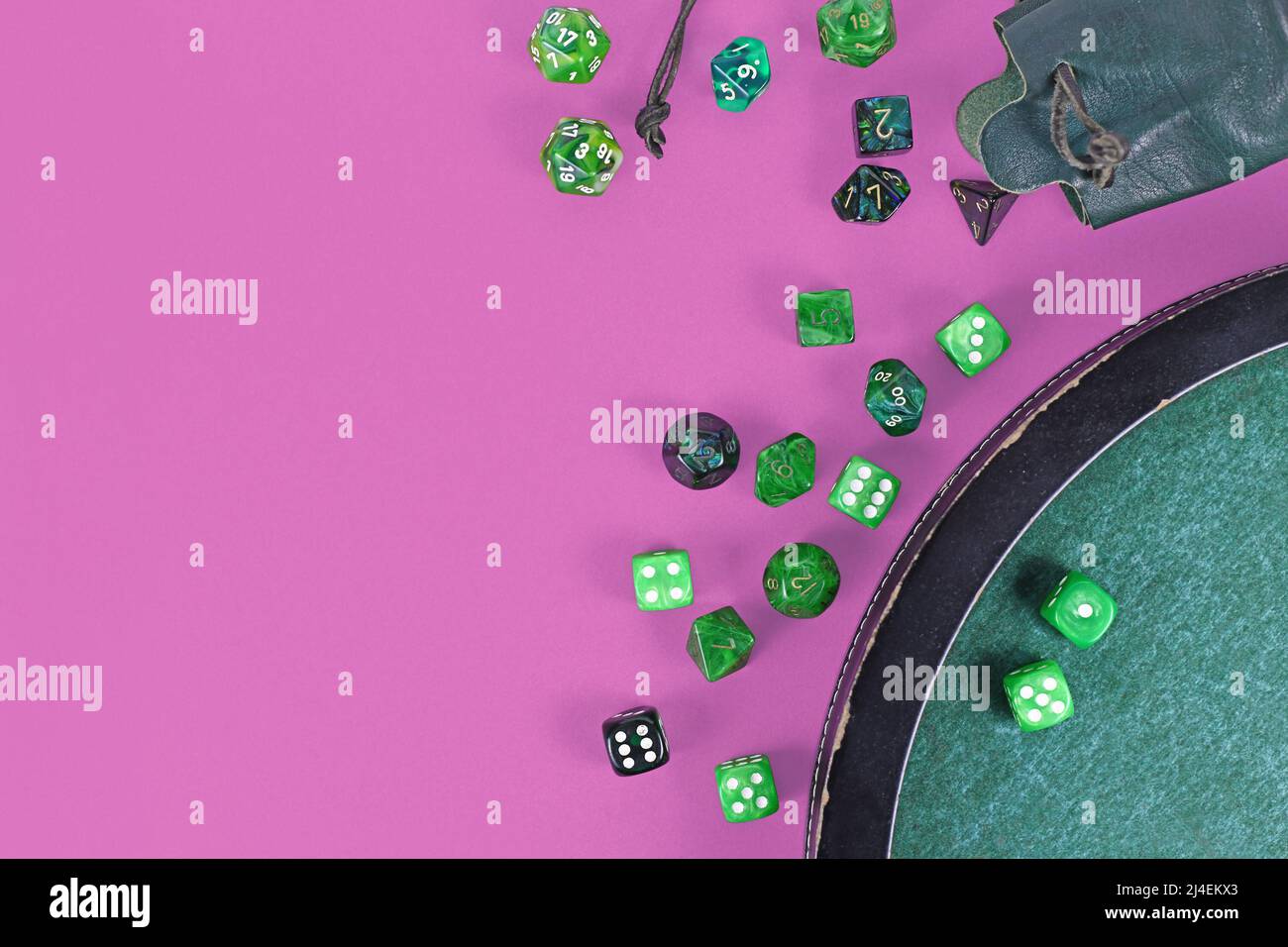 Verschiedene grüne Rollenspiel-Würfel auf violettem Hintergrund Stockfoto