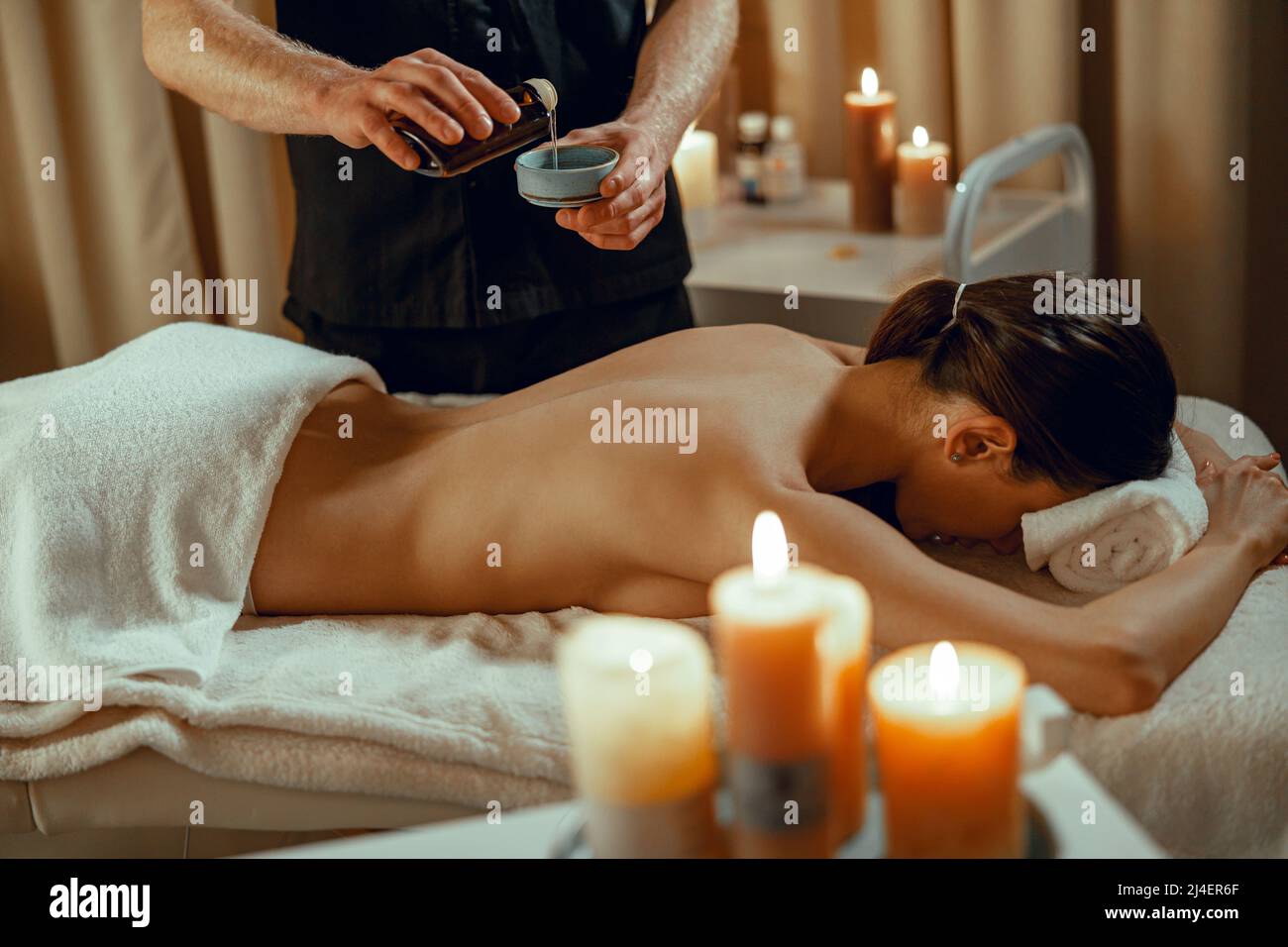 Masseur Mann Therapeut Vorbereitung warmen Kraut infundiert Öl, um Wirbelsäule Massage zu machen Stockfoto