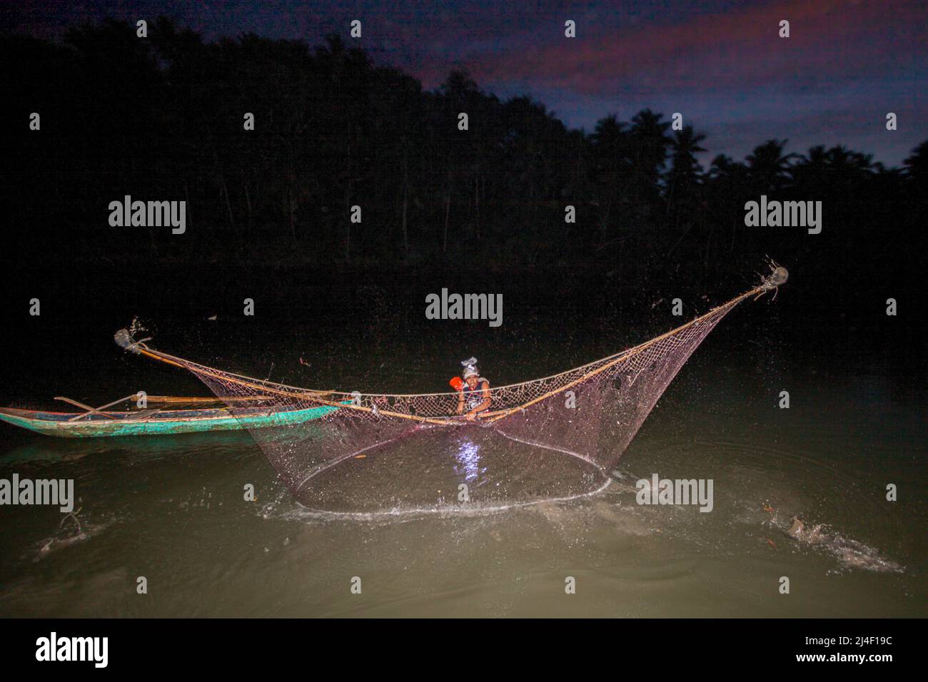 Ein einheimischer Fischer am Ubod River, der sein Netz in der Abenddämmerung auswirft, Donsol, Provinz Sorsogon, Luzon, Philippinen. Stockfoto