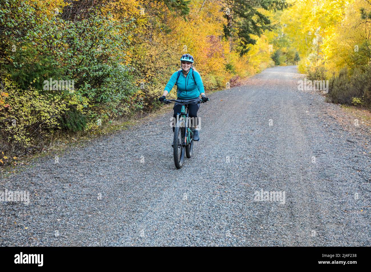 Eine Frau mittleren Alters, die mit dem Mountainbike auf dem Cascades-to-Palouse-Trail in den Eastern Cascade Mountains entlang des Yakima River, Washington, fährt. Stockfoto