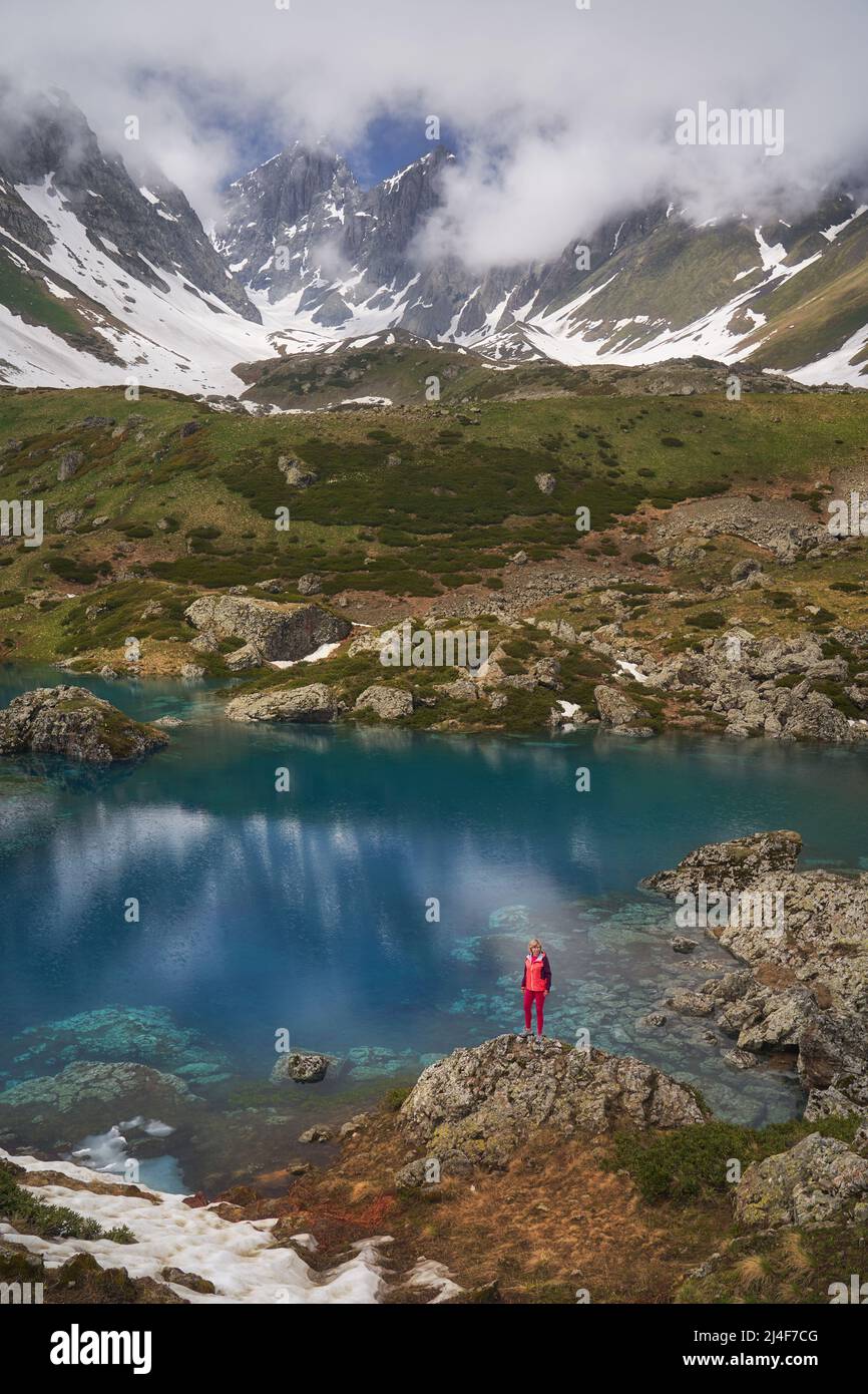 Wanderfrau in roter Jacke, die am schönen See in den Bergen steht. Stockfoto