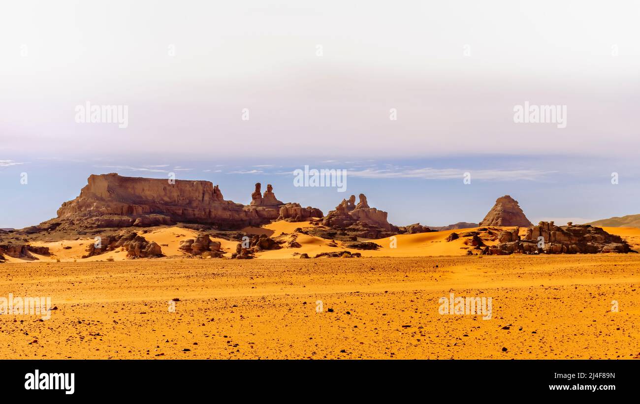 Panoramablick auf die Sahara-Wüste. Menschengeformte Felsberge in Tadrart Rouge, Tassili n'Ajjer. Orange Farbe reg Sandsteine. Blauer Himmel. Stockfoto