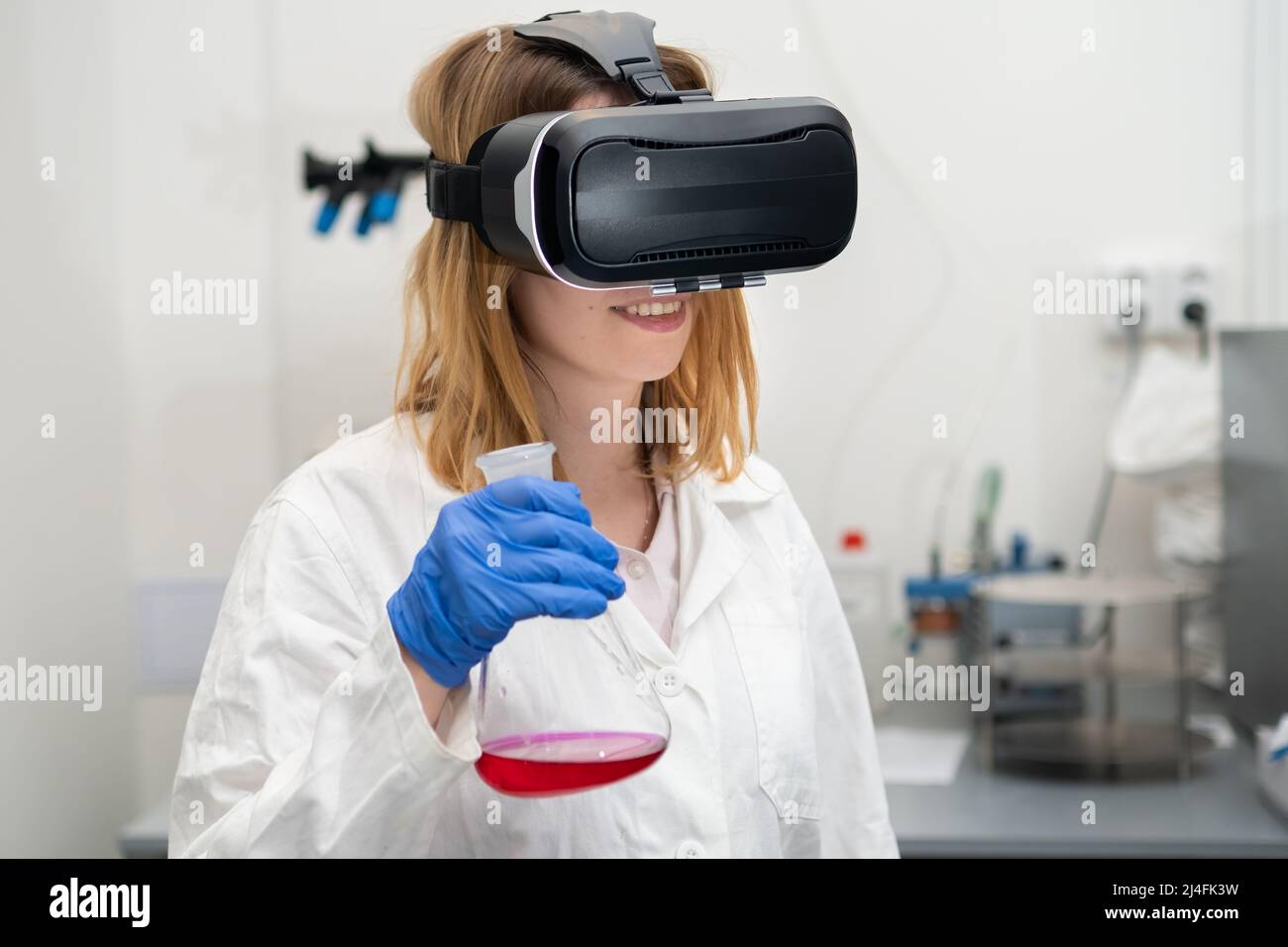 Wissenschaftler in VR-Googles, Laborkittel und Gummihandschuhen verwalten die virtuelle Schnittstelle. Digitale Technologie NFT Spiel und Unterhaltung Stockfoto