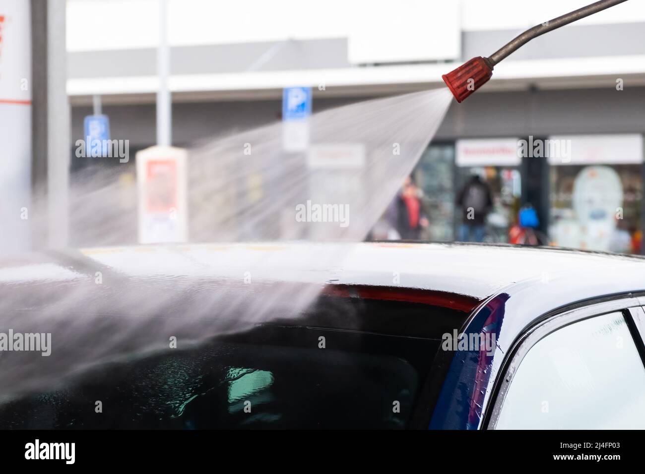 Reinigung des Automobils mit Druckwasserstrahl bei der Autowaschanlage. Elektrofahrzeug in Garage gewaschen Nahansicht Stockfoto