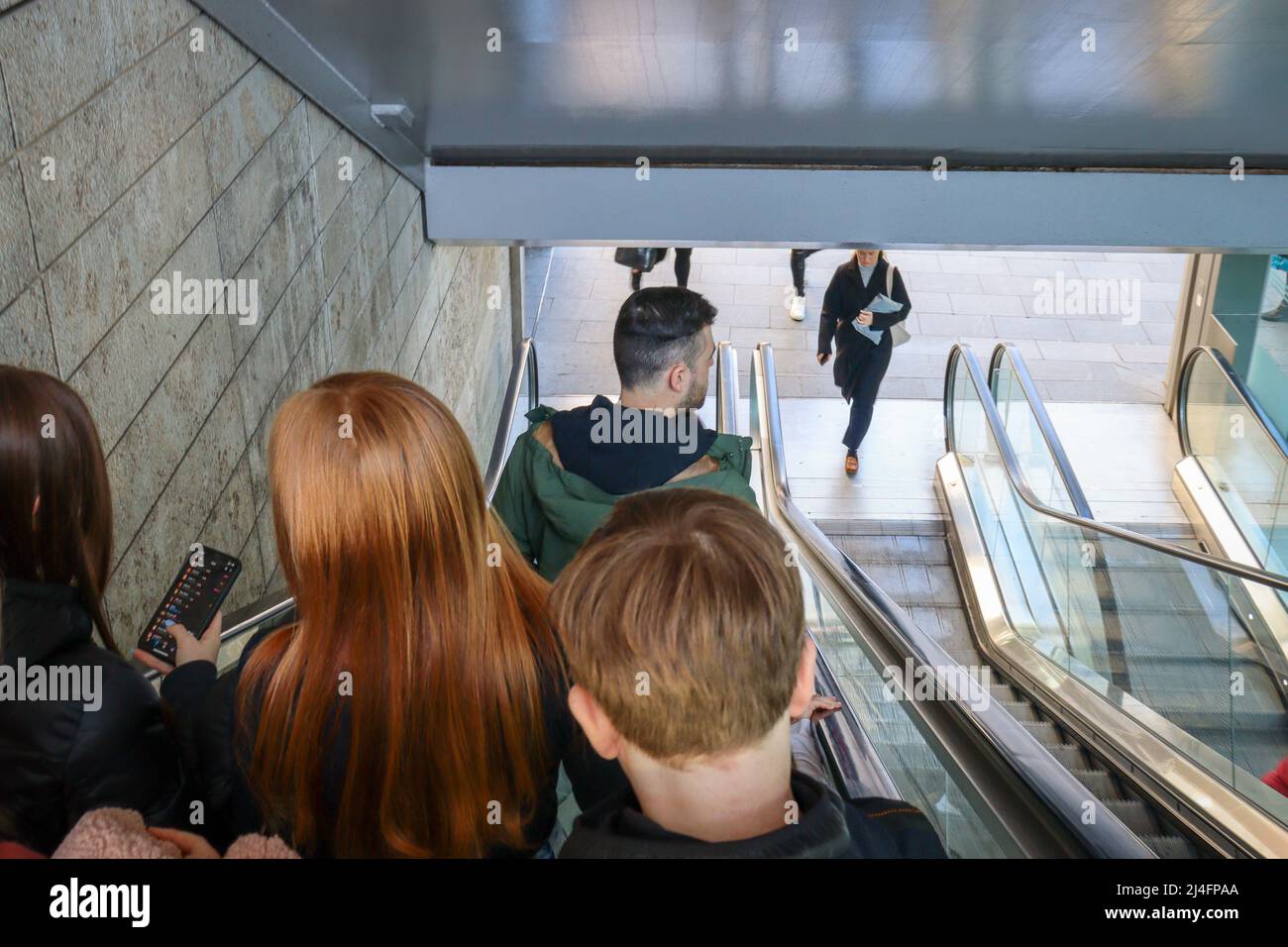 Personen, die mit einer Rolltreppe hinunterfahren Stockfoto