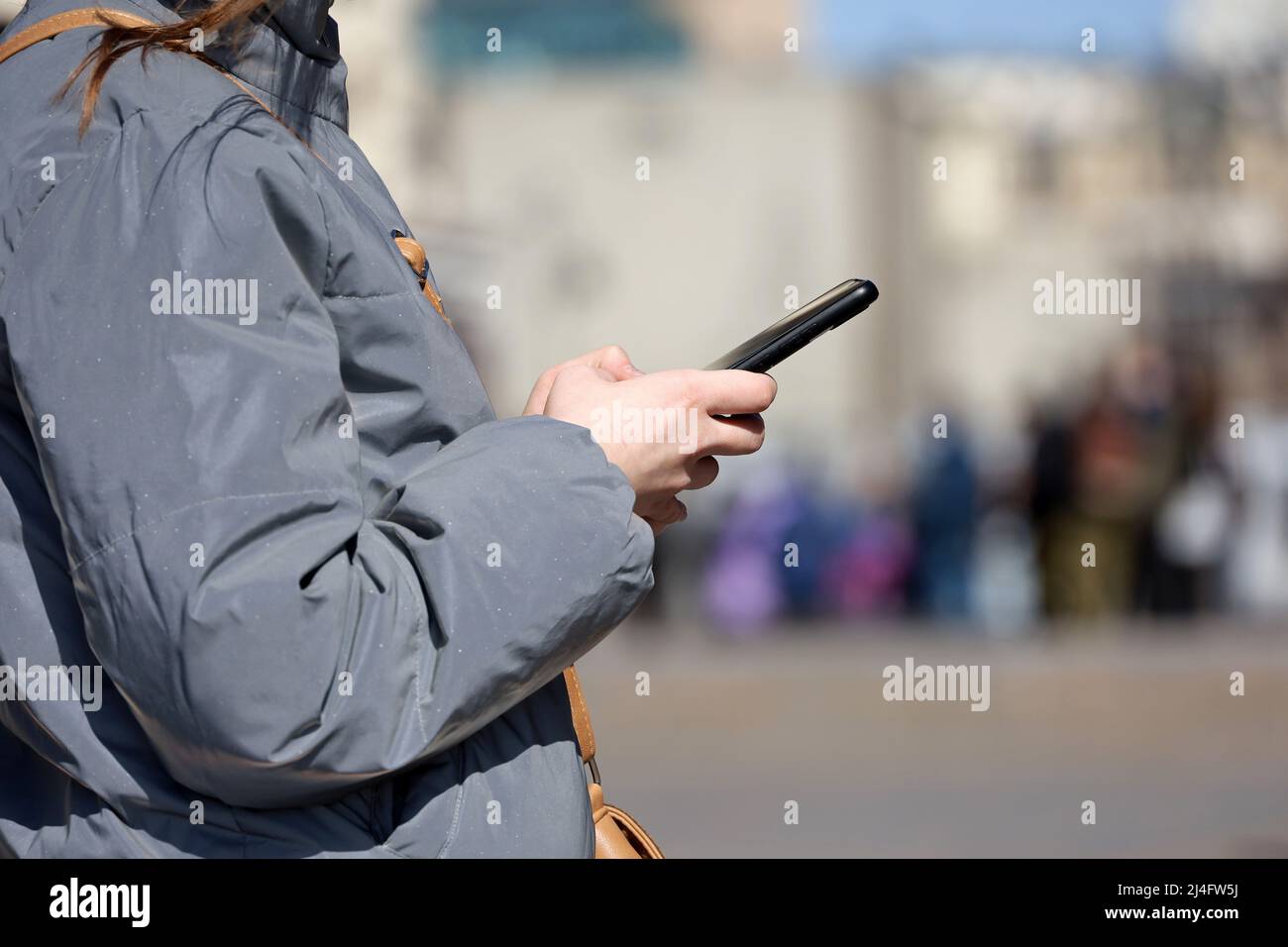 Weibliche Hände mit Smartphone Nahaufnahme auf verschwommenen Menschen Hintergrund. Mädchen, die auf einer Stadtstraße ein Mobiltelefon benutzt Stockfoto