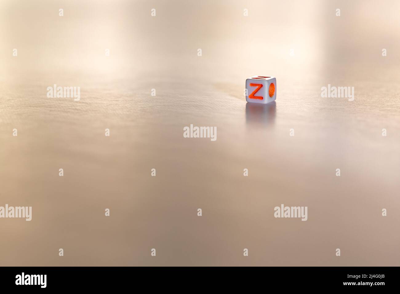 Würfelförmige Spielwürfel mit dem orangefarbenen Buchstaben Z auf einem weißen isolierten Hintergrund. Freitextbereich unten.Konzept der Generation Z. Stockfoto
