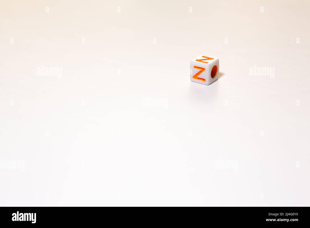 Würfelförmige Spielwürfel mit dem orangefarbenen Buchstaben Z auf einem weißen isolierten Hintergrund. Freier Textbereich unten und links. Konzept der Generation Z. Stockfoto