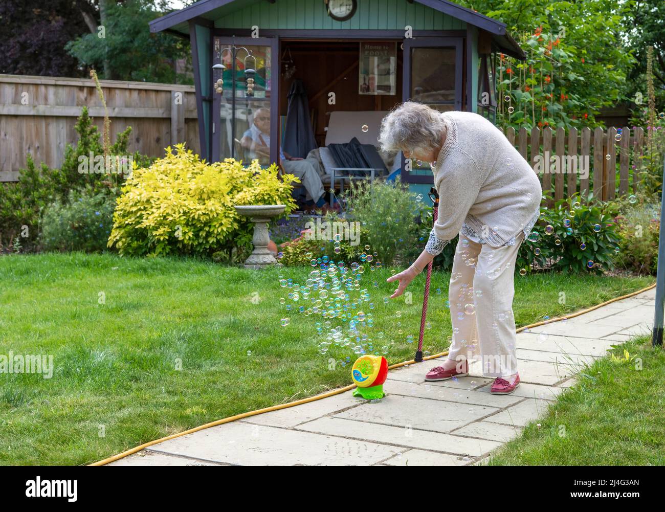 Großmutter, die Spaß mit Blasen im Garten hat und beweist, dass du nie zu alt bist, um ein Kind zu sein! Konzept der jungen Menschen im Herzen. Stockfoto