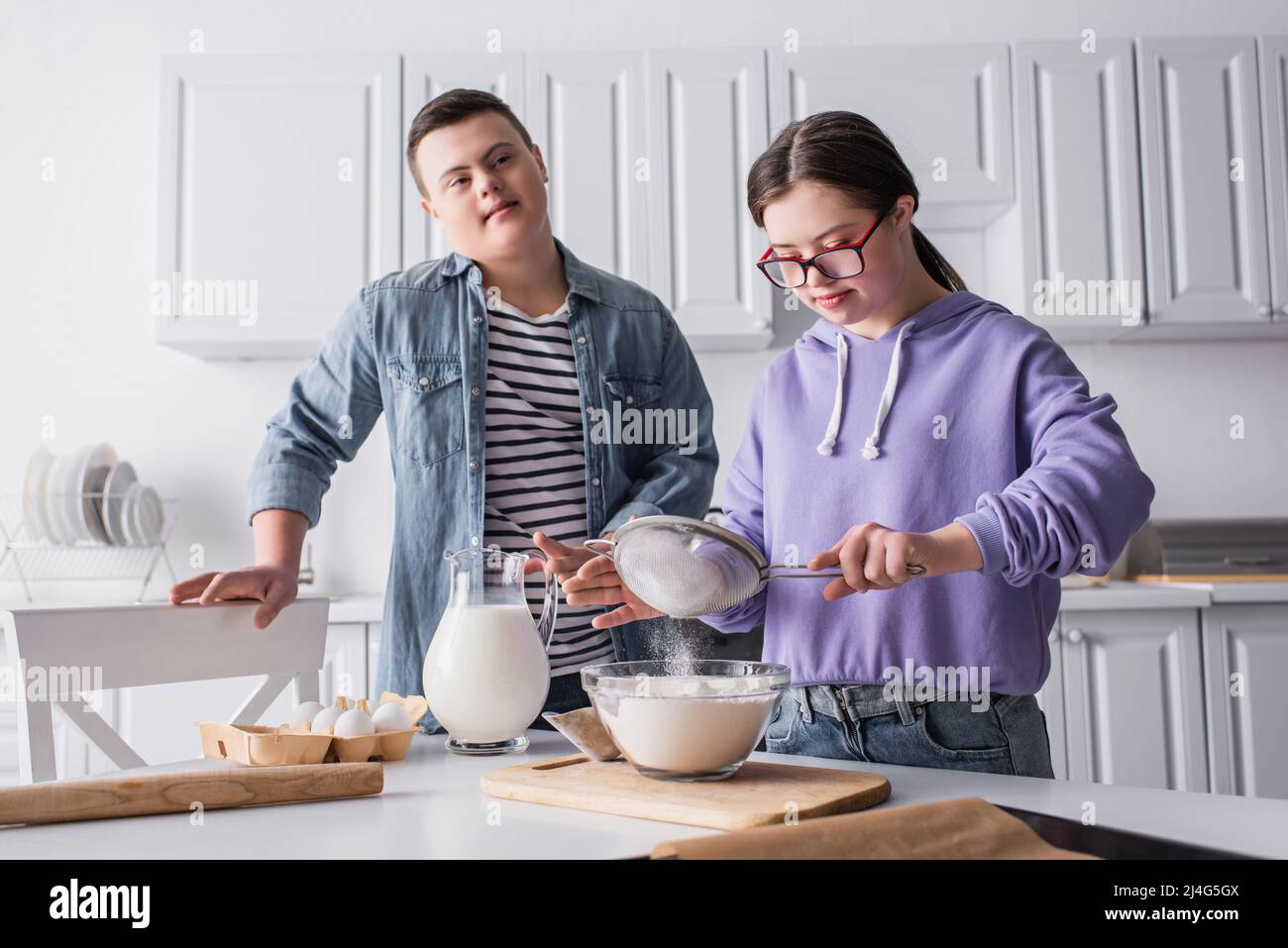 Teen Mädchen mit Down-Syndrom Kochen in der Nähe Freund in der Küche Stockfoto