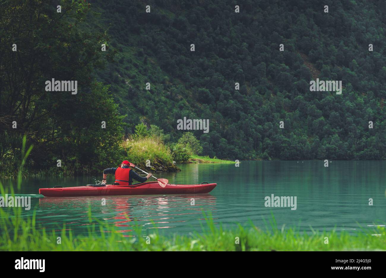 Kaukasischer Kayaker in seinem 30s auf einer Reise entlang des norwegischen Gletschersees. Sport und Erholung Thema. Stockfoto