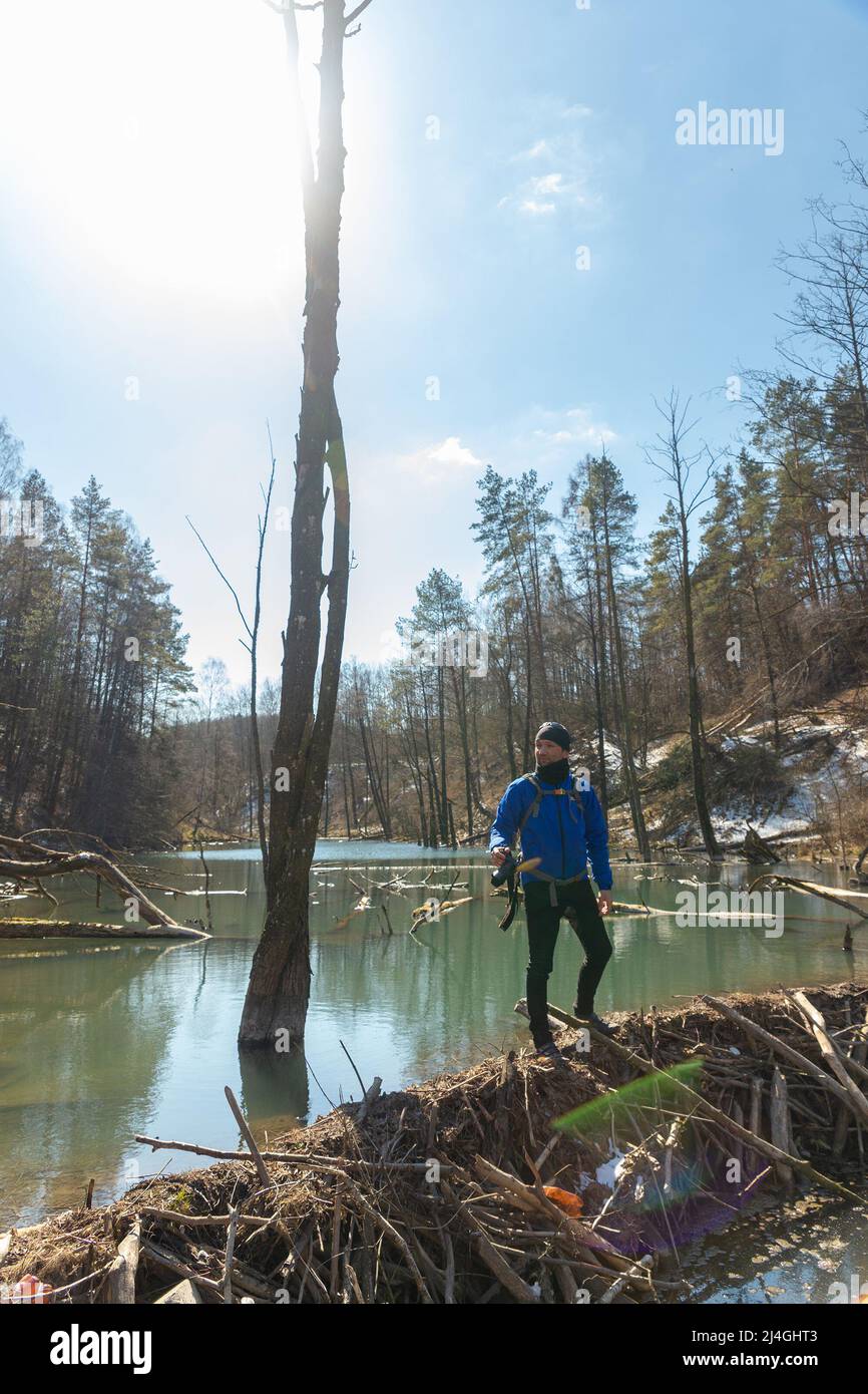 Fotograf mit Rucksack auf den Schultern und mit DSLR-Kamera in seinem und geht entlang der Biber-Mutter und Suche nach einem Bild Stockfoto