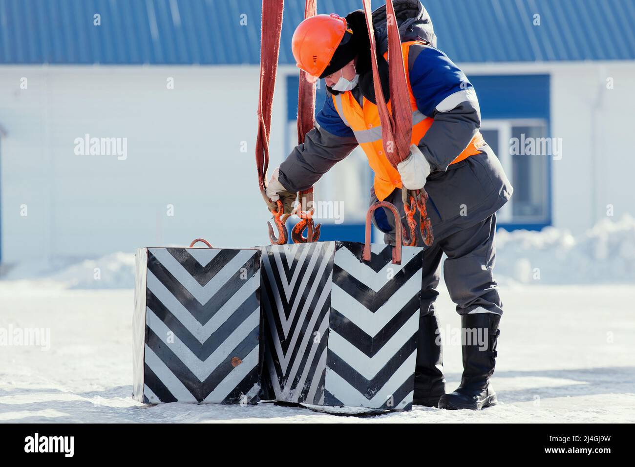 Die Arbeitsklastenhaken werden mit dem Haken mit den Schlingen beladen. Arbeiten am Entladen von Fracht. Training von Slingern. Wintertag. Stockfoto