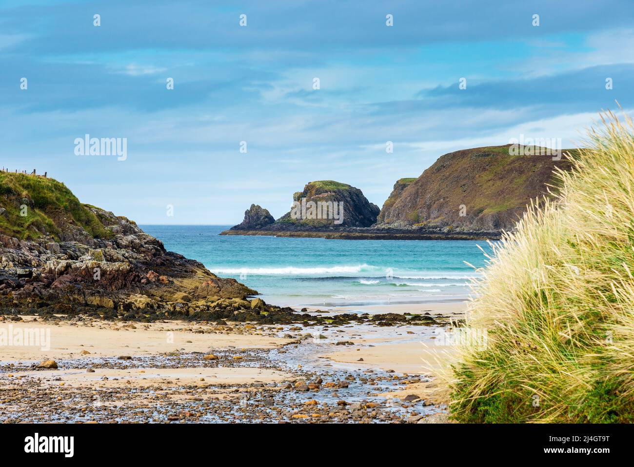 Die glitzernde weiße Brandung steht im Kontrast zum blauen Meer, während die Wellen am Sandstrand der Farr Bay brechen. Stockfoto