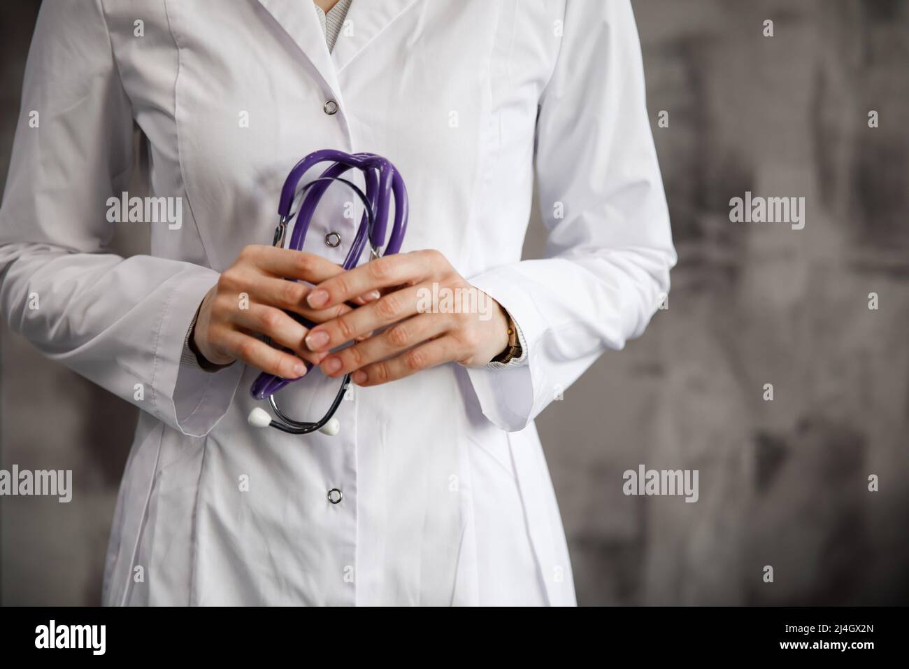 Nahaufnahme einer Ärztin mit einem Stethoskop in den Händen. Vor dem Hintergrund eines verschwommenen Krankenhauses. Stockfoto