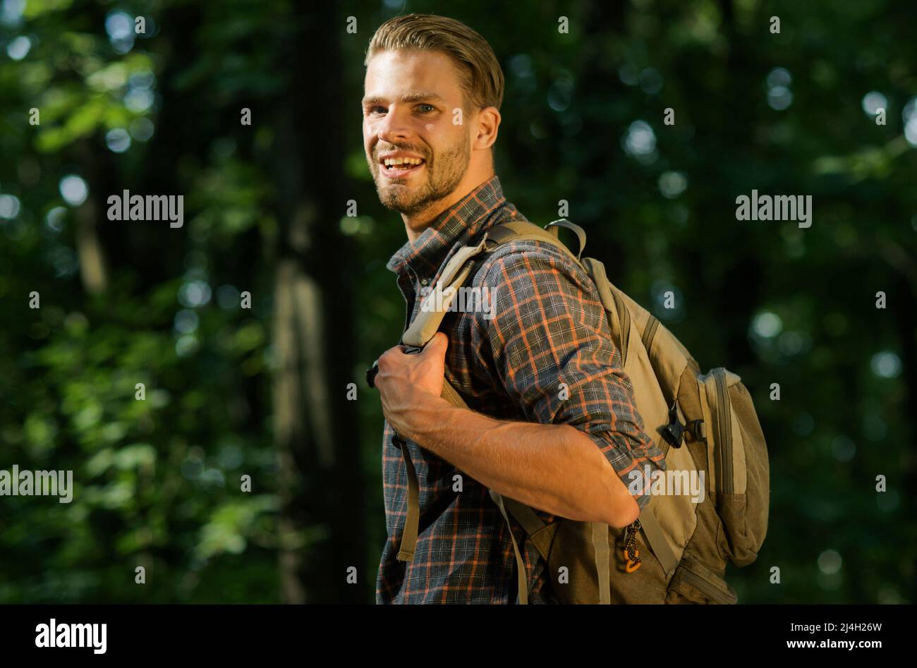 Glücklicher männlicher Reisender mit Rucksack, der im Wald spazierengeht. Tourismus, Reisen, Abenteuer, gesunder Lebensstil. Stockfoto