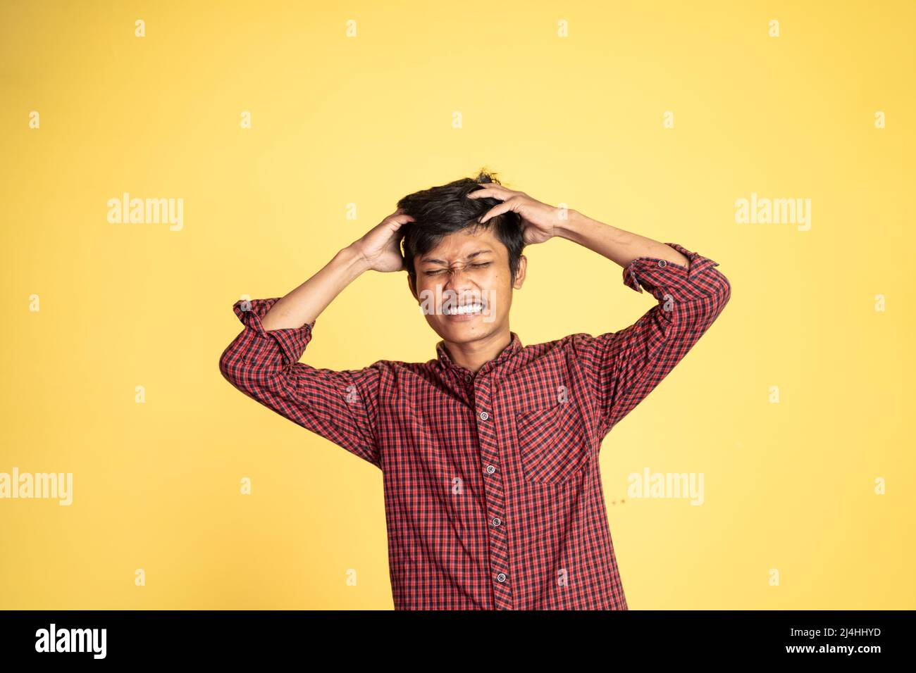 Gestresster junger asiatischer Mann, der den Kopf hält Stockfoto