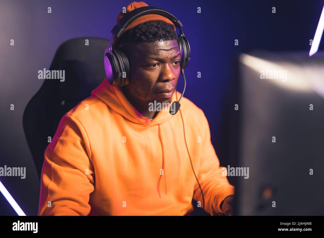 Junger afroamerikanischer Mann spielt und streamt online Videospiel Cyber Sport Medium Nahaufnahme drinnen. Hochwertige Fotos Stockfoto