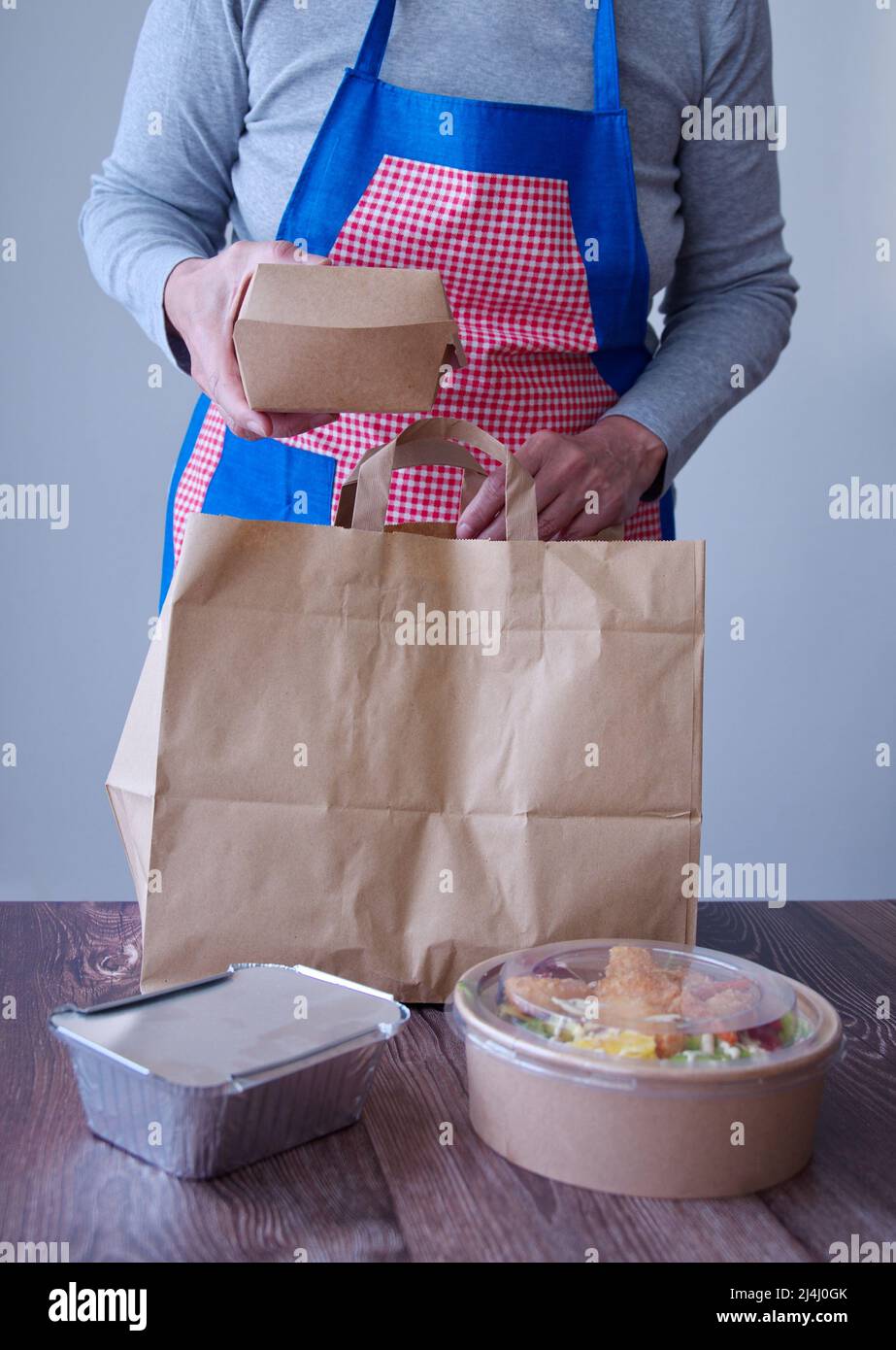Mittelteil einer Frau, die Essen zum Mitnehmen in einem Papierbeutel zubereitete Stockfoto