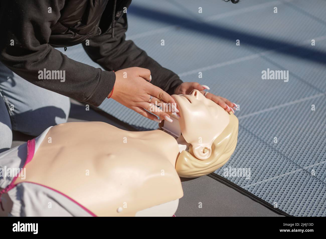 Details mit den Händen einer Studentin, die lernt, wie man eine kardiopulmonale Reanimation (CPR) an einer Schaufensterpuppe zu Bildungszwecken durchführt. Stockfoto