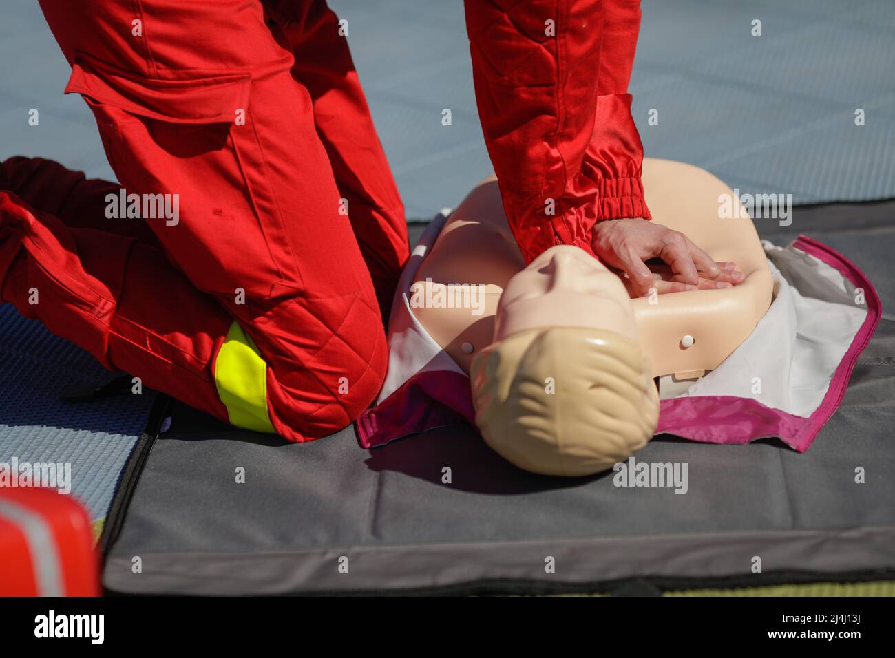 Details mit den Händen eines Notarzthelfers, der die kardiopulmonale Reanimation (CPR) an einer Schaufensterpuppe zu Schulungszwecken durchführt. Stockfoto