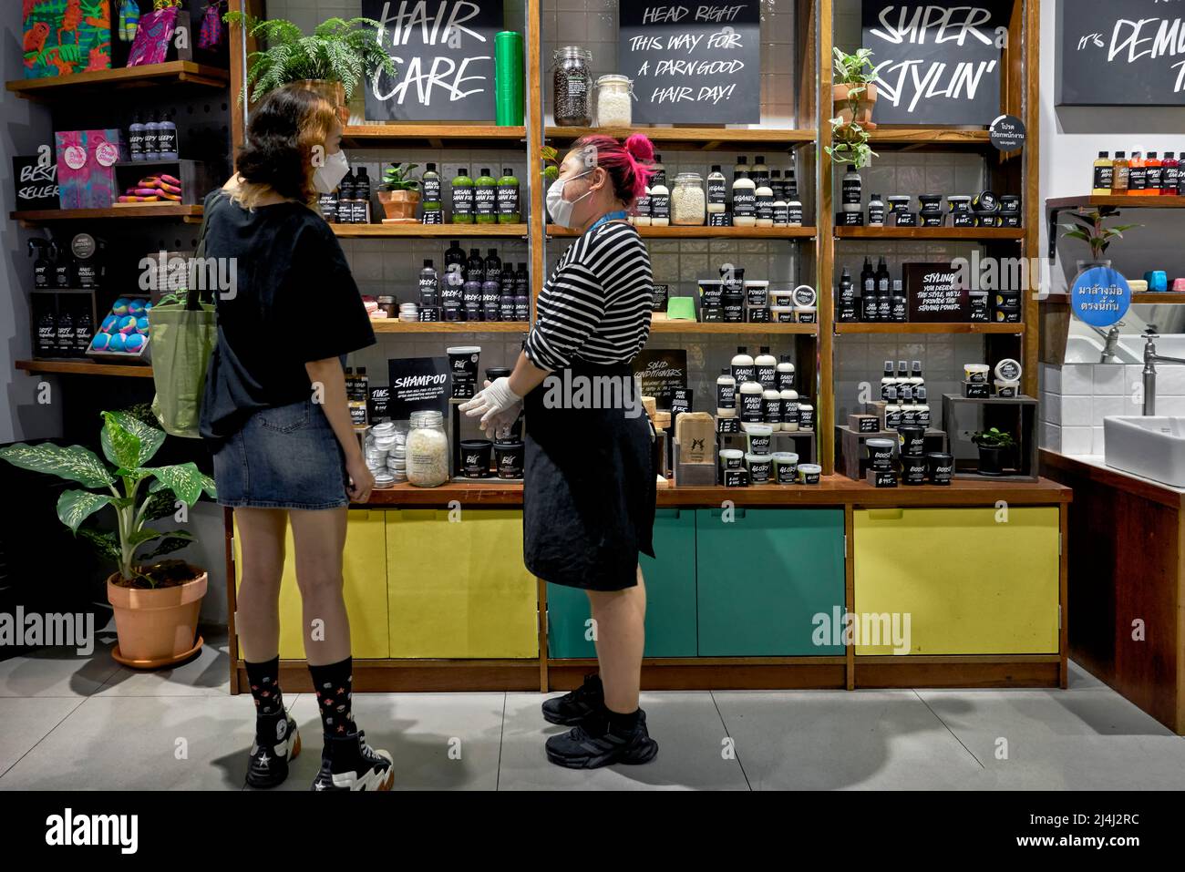 Inneneinrichtung des Hautpflegeshops mit einer Kundin, die mit einem Mitarbeiter über die Produkte spricht Stockfoto