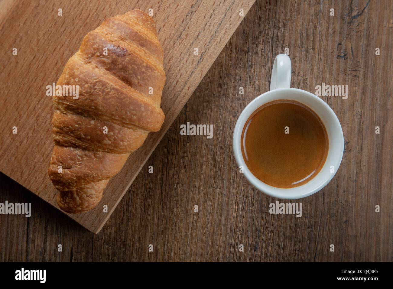 Croissant mit Espresso in weißer Tasse, Draufsicht Stockfoto