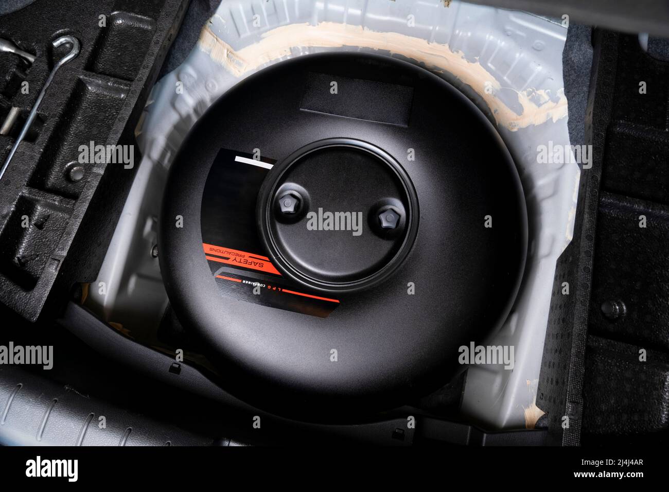 Schwarzer Treibgasbehälter in Form eines Donuts in einem Reserveradloch im Kofferraum eines Autos Stockfoto