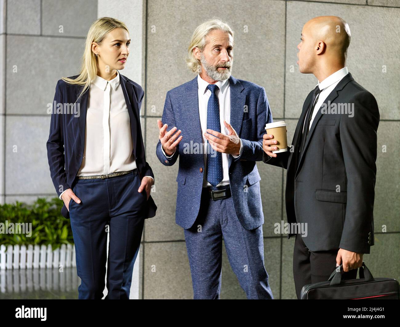 Multiethnische Geschäftsleute Pendler, die in einem modernen Bürogebäude stehen, unterhalten sich Stockfoto