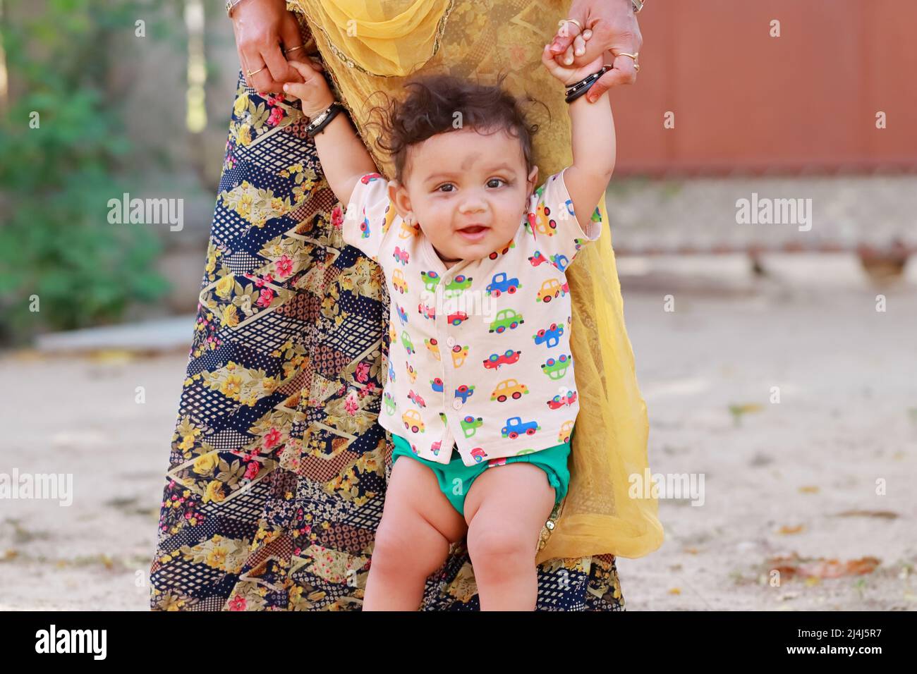Nahaufnahme eines Portraitfotos eines kleinen neugeborenen niedlichen Hindu-Babys, das mit lächelndem Gesicht die Hand der Mutter hält, indien Stockfoto