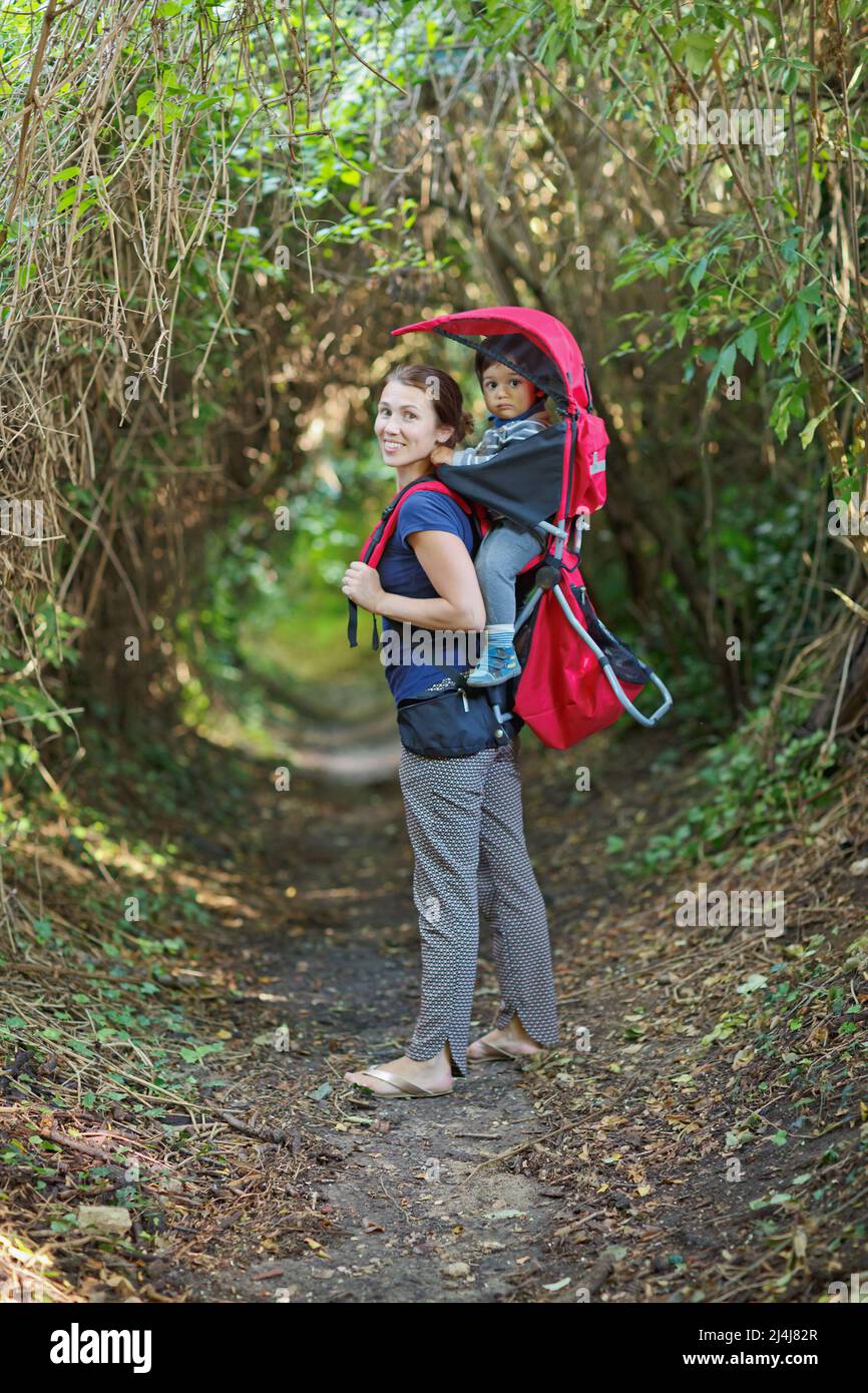 Mutter mit Kleinkind Kind im Rucksackträger wandert im Wald Stockfoto