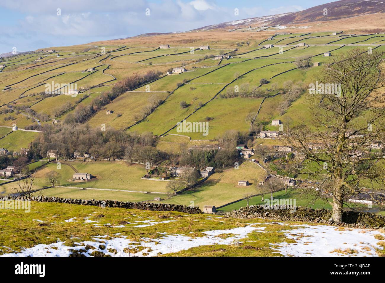 Swaledale, Yorkshire Dales National Park, schneebedeckte Hügel über einem Flickenteppich aus Trockensteinmauern gesäumten Feldern und Weiden mit ikonischen Steinhäusern Stockfoto