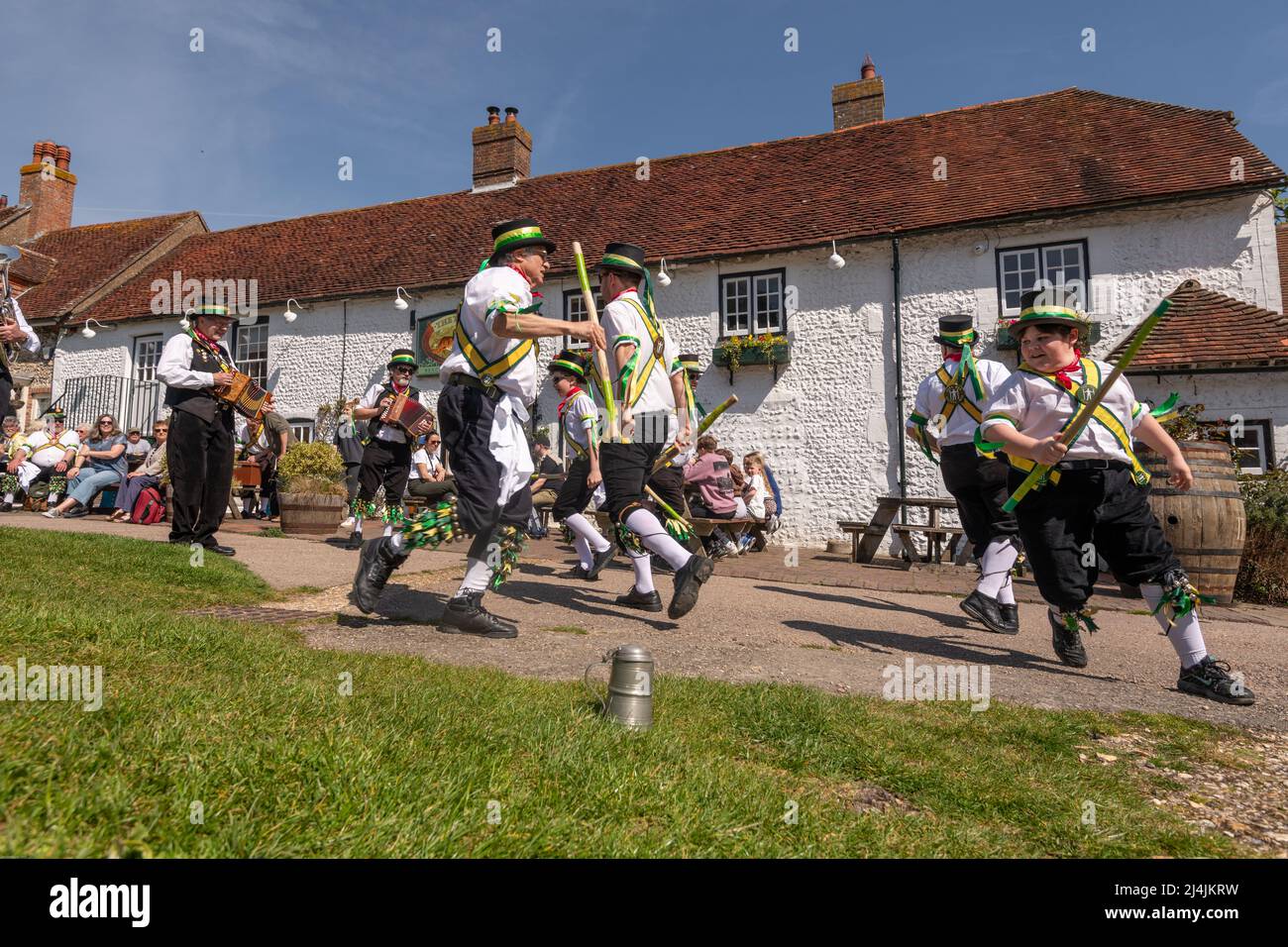 Die Aufführung der Longman Morris Dancer auf dem Dorfgrün vor dem Tiger Inn, im East Dean East Sussex. Aufgrund von Covid-Einschränkungen haben sie nur Biene Stockfoto