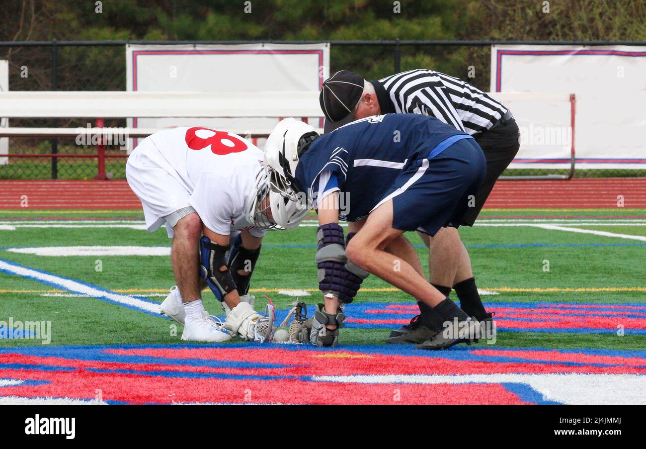 High School Boys, die bereit sind, sich in einem Lacrosse-Spiel zu stellen, um den Ball offiziell zu platzieren. Stockfoto