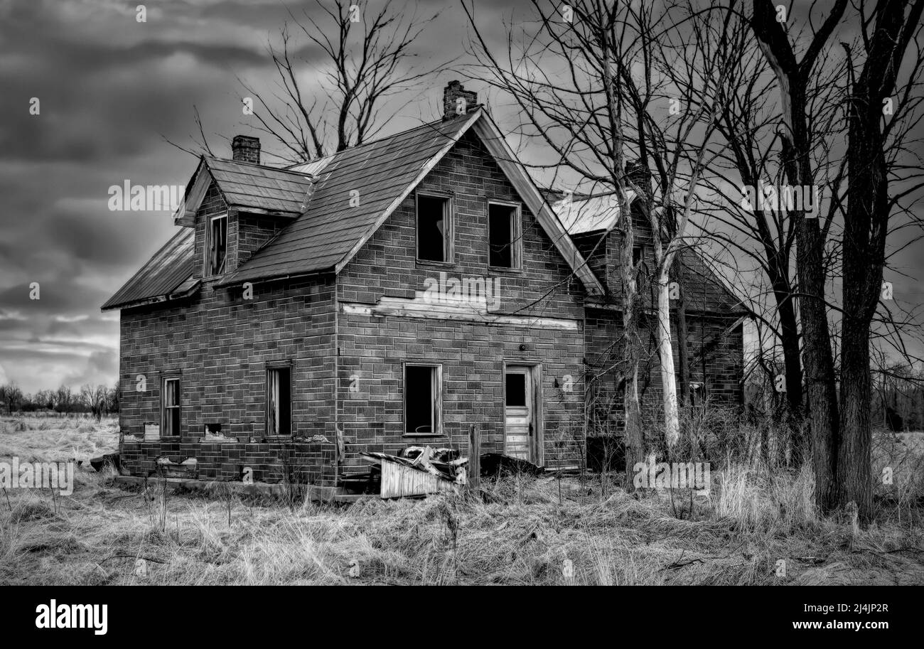 Ein altes schwarz-weiß verlassene gruselig aussehende Bauernhaus im Winter auf einem Bauernhof im ländlichen Kanada Stockfoto