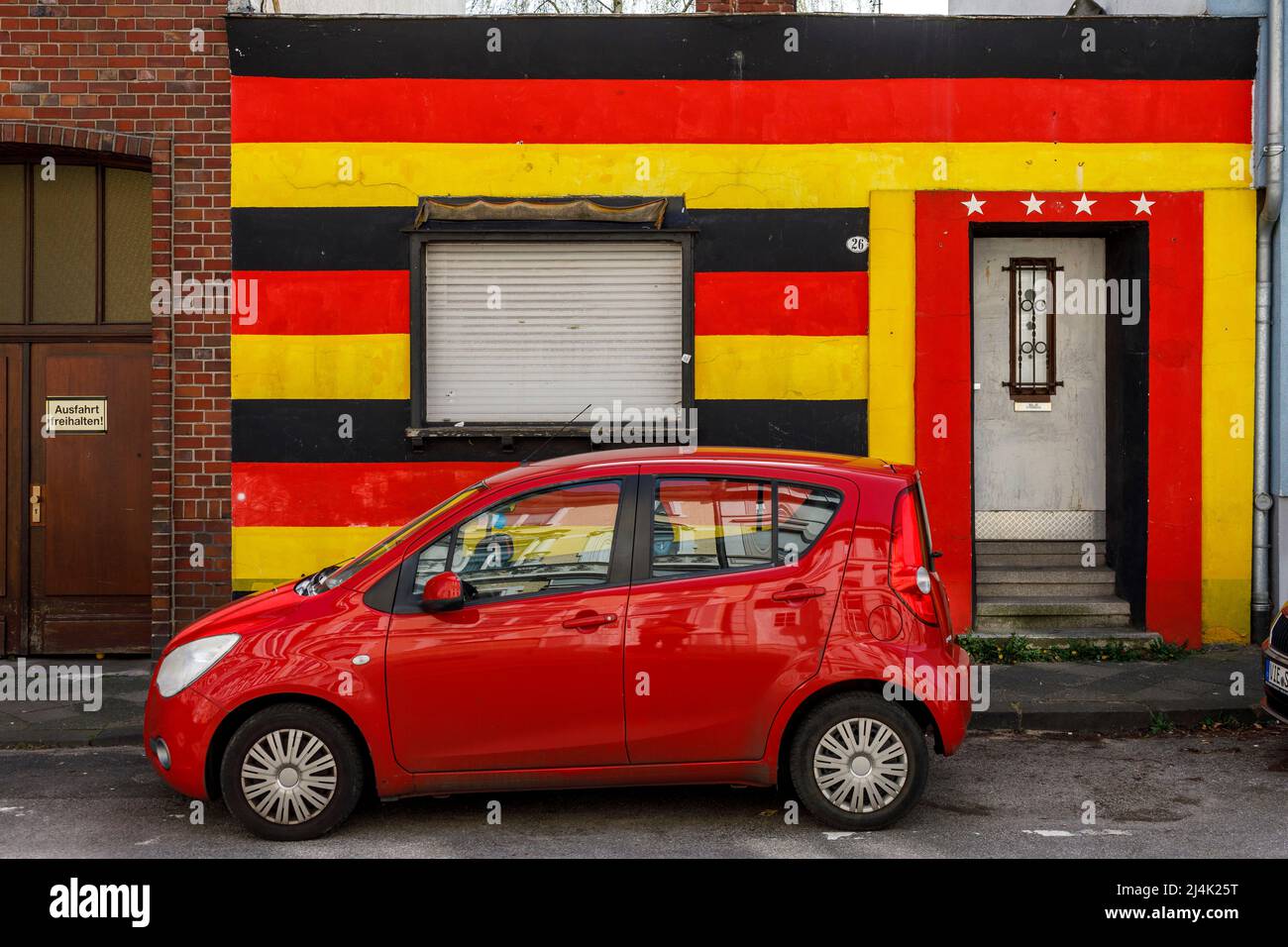 Vorderseite eines Wohnhauses in den deutschen Nationalfarben und 4 Sterne über der Eingangstür. Hommage an die Fußballweltmeisterin. Stockfoto
