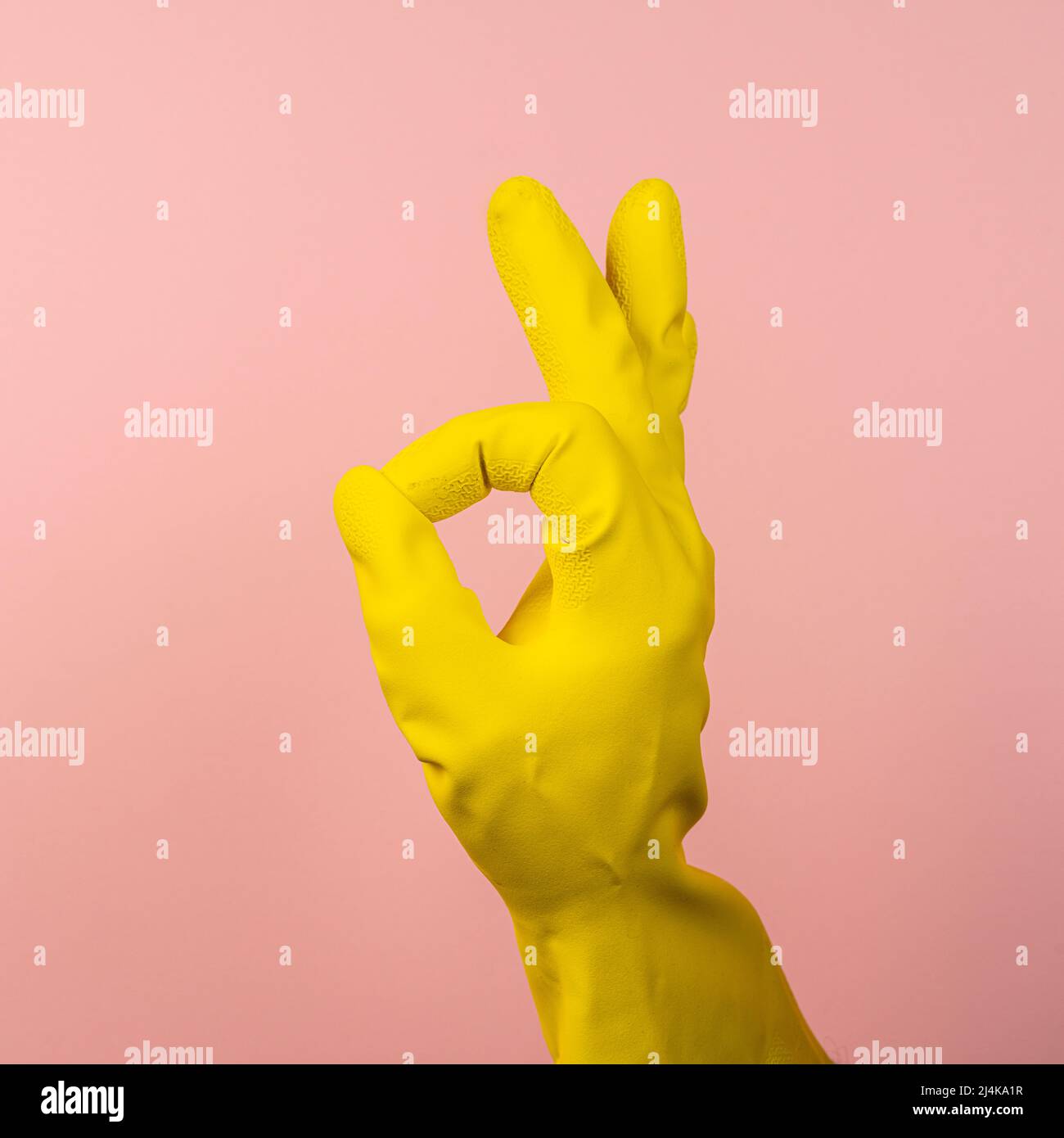 Die OK-Geste mit einer Hand, die einen gelben Gummihandschuh trägt Stockfoto
